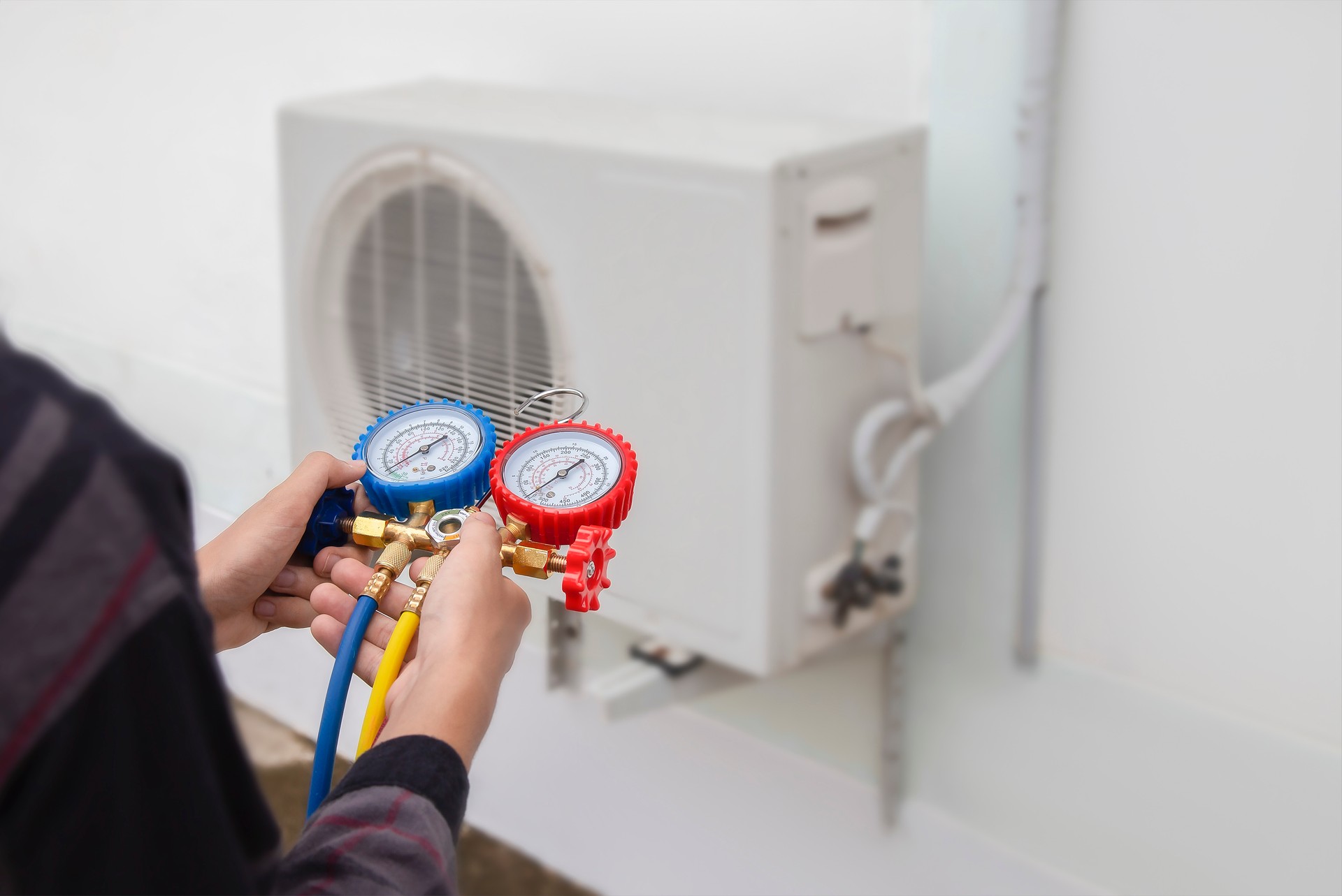 Air conditioning, HVAC service technician using gauges to check refrigerant and add refrigerant.