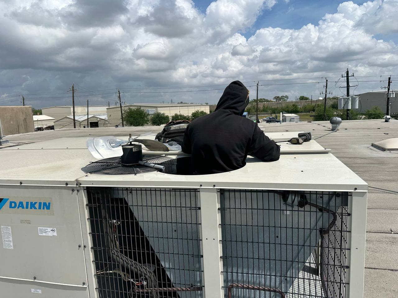 APCA technician replacing a condenser fan motor on a commercial Daikin rooftop HVAC unit