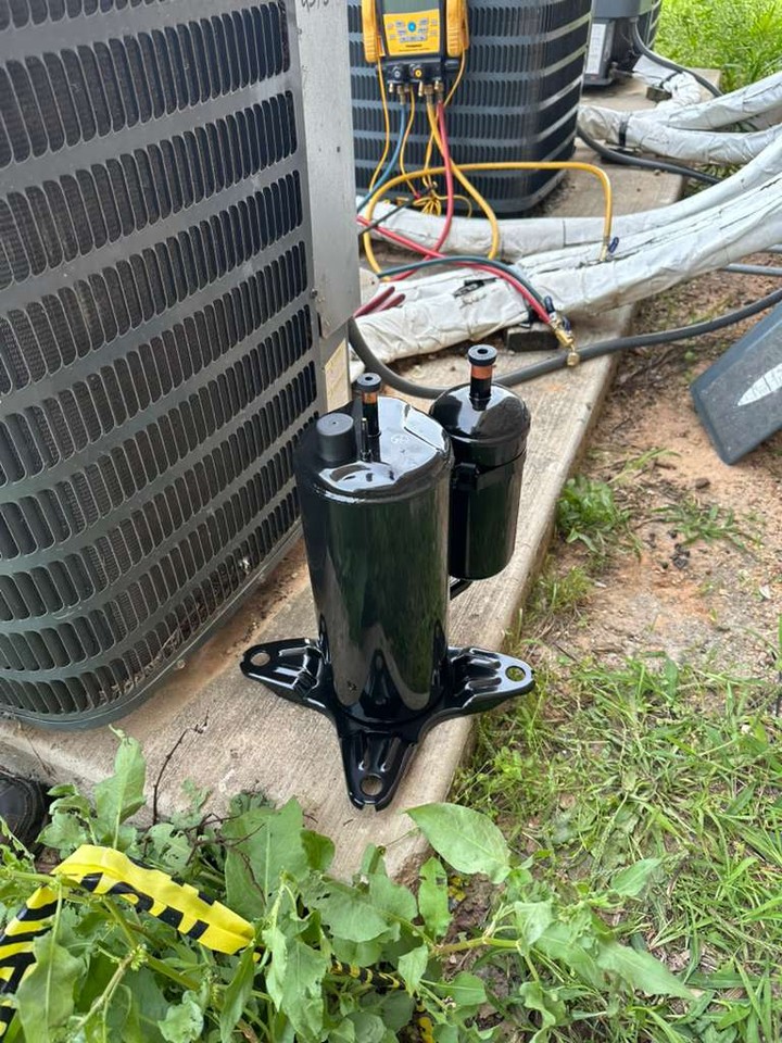 Replacement air-conditioning compressors beside an outdoor condenser during residential repair work